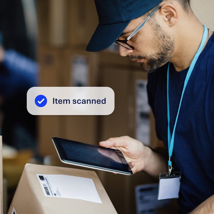 A male delivery driver scanning a parcel with a mobile device. The image show 'Item Scanned' overlayed.
